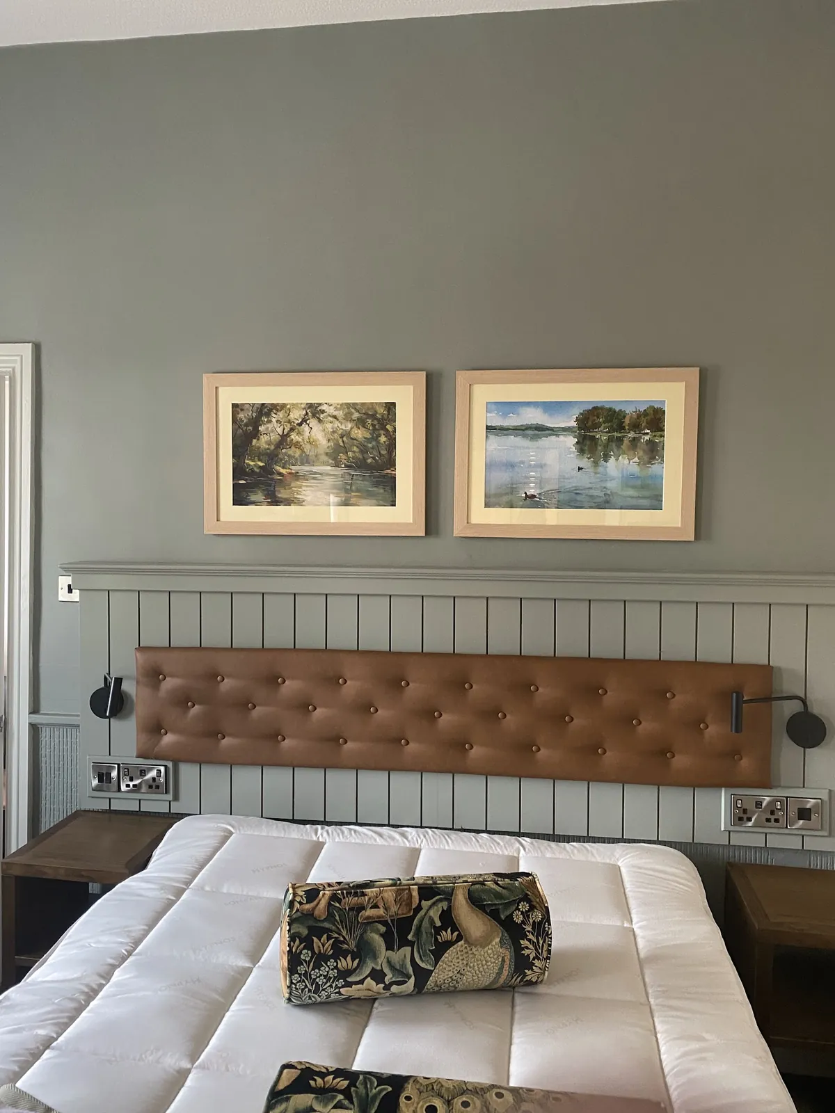 Bedroom with painted panelling and a pair of framed pictures