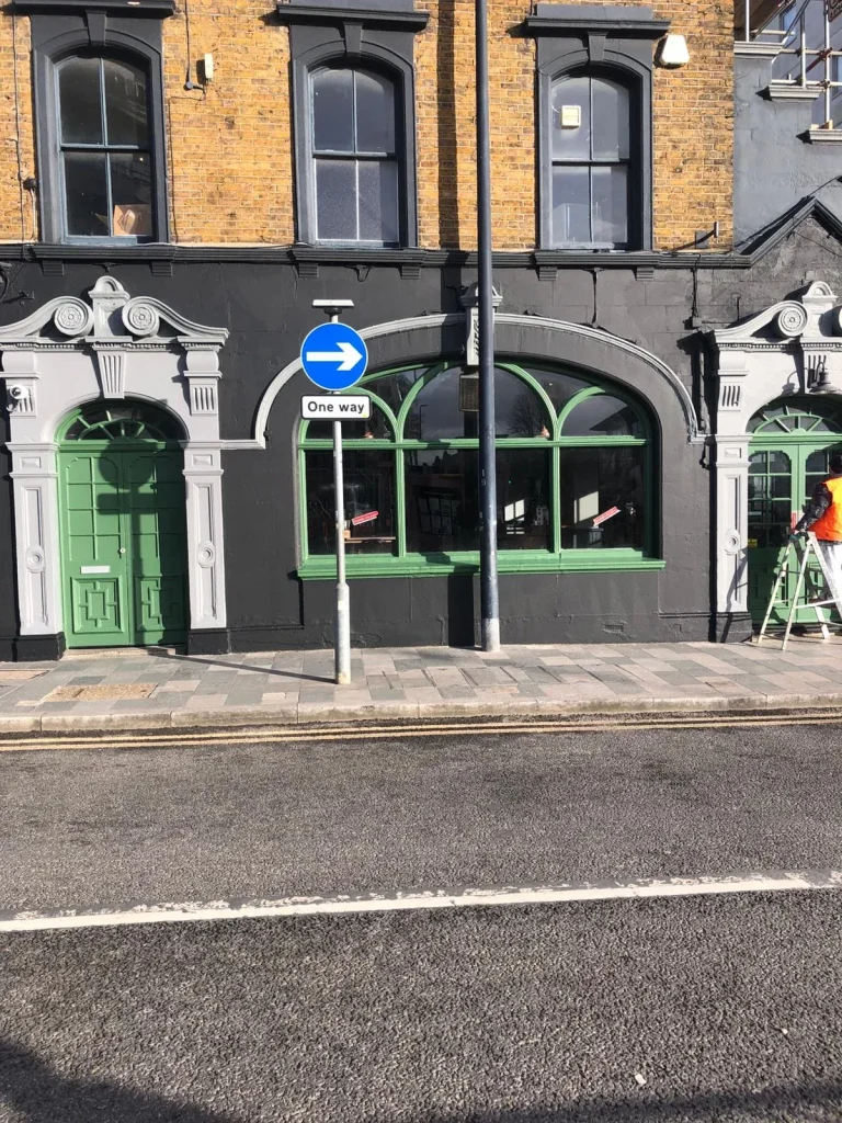 Shopfront painted black with green doors and white decorative detailing