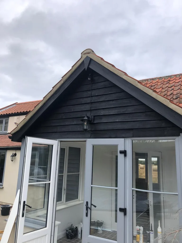 Black timber outbuilding with white painted doors