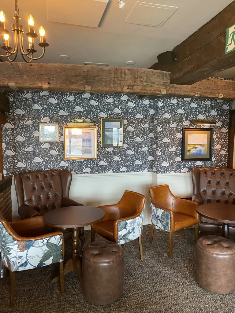 Floral wallpaper above cream walls in a timber-framed room