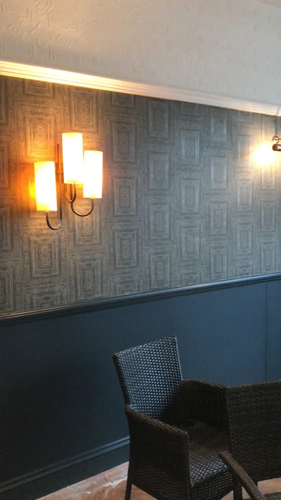 Geometric wallpaper above navy panelling with wall lights