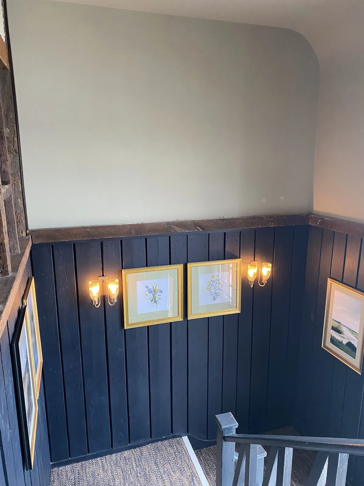 Navy painted panelling with gold wall lights and framed pictures
