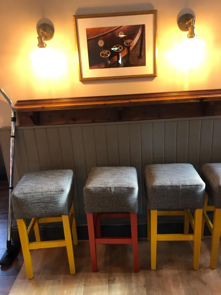 Painted panelling and woodwork behind a row of bar stools with coloured legs