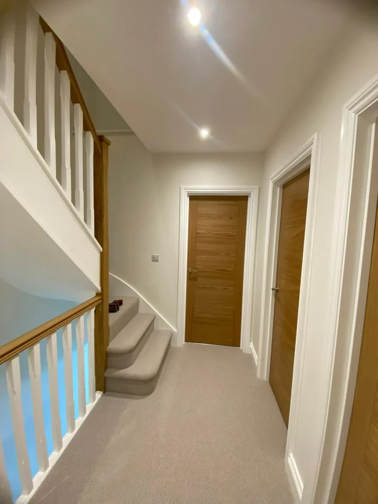 Staircase and landing with white walls and oak doors