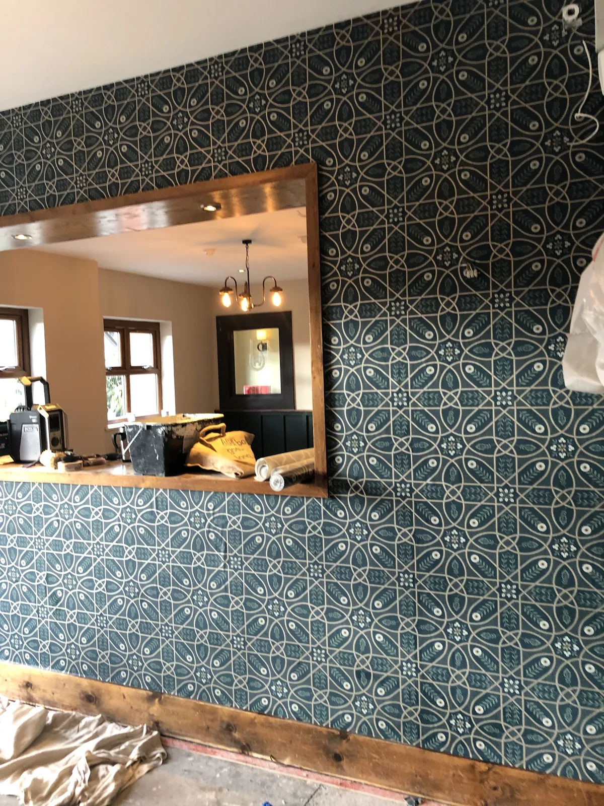 Teal geometric wallpaper around a serving hatch